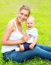 Happy smiling mother and son child sitting on grass in summer Royalty Free Stock Photo