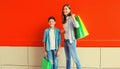 Happy smiling mother and son child together with shopping bags on red wall background Royalty Free Stock Photo