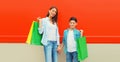 Happy smiling mother and son child together with shopping bags on red wall background Royalty Free Stock Photo