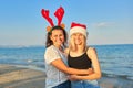 Happy mother and teen daughter in Santa Claus hat on beach, New Year Christmas holidays Royalty Free Stock Photo