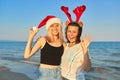 Happy mother and teen daughter in Santa Claus hat on beach, New Year Christmas holidays Royalty Free Stock Photo