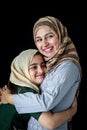 Happy smiling Muslim girl with beautiful eyes wear hijab scarf and traditional costume hugging with her mother, warm love in Royalty Free Stock Photo