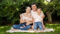 Happy smiling parents with two sons sitting on grass in park and having good time together. Parenting, family, children Royalty Free Stock Photo