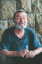 Happy and smiling poor homeless man sitting in the shadow of the building on the urban street in the city Royalty Free Stock Photo