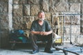 Happy and smiling poor homeless man sitting in the shadow of the building on the urban street in the city Royalty Free Stock Photo