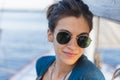 Happy smiling portrait of a beautiful young girl in sunglasses on a yacht or boat on the coast with the sea in the background Royalty Free Stock Photo