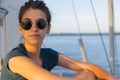 Happy smiling portrait of a beautiful young girl in sunglasses on a yacht or boat on the coast with the sea in the background Royalty Free Stock Photo