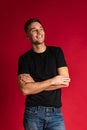 Portrait of young handsome sportive man in black t-shirt and blue jeans posing isolated on red studio background. Royalty Free Stock Photo