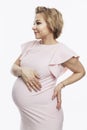 Happy smiling pregnant blonde woman stands and touches big belly. Waiting for the birth of a baby. White background. Vertical