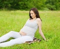 Happy smiling pregnant woman on grass in summer Royalty Free Stock Photo