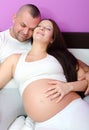 Happy smiling pregnant woman and her husband lying on bed Royalty Free Stock Photo
