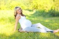 Happy smiling pregnant woman outdoors on grass in sunny summer Royalty Free Stock Photo