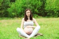 Happy smiling pregnant woman sitting on grass doing yoga in summer Royalty Free Stock Photo