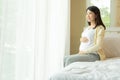 Happy smiling pregnant woman touching belly sitting in bed at home Royalty Free Stock Photo