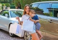 Happy smiling preteen girl with shopping bags holding her little brother coming back after shopping by car. Royalty Free Stock Photo