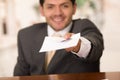 Happy smiling receptionist in hotel giving key to guest and papers to sign Royalty Free Stock Photo