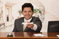 Happy smiling receptionist in hotel giving key to guest and papers to sign, hotel background Royalty Free Stock Photo
