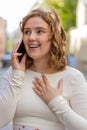 Happy young woman having remote conversation talking on smartphone good news gossip in city street Royalty Free Stock Photo