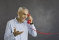 Happy smiling retired senior man talking to someone on red retro landline telephone Royalty Free Stock Photo