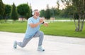 Happy smiling retired sportsman in headphones doing workout in park on sunny summer day