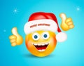 Happy smiling round face wearing a red santa claus hat with lettering merry christmas showing thumbs up on bright blue background. Royalty Free Stock Photo