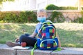 Happy smiling schoolboy on the background of school. School boy wearing medical face mask to health protection. Back to school. Royalty Free Stock Photo