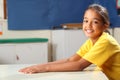 Happy smiling schoolgirl 10 in yellow at her desk