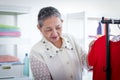 Happy smiling senior elderly woman housewife hanging clothes indoor to dry, older Asian female doing laundry at laundry room, Royalty Free Stock Photo