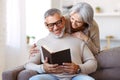 Happy smiling senior family couple in love reading book together at home Royalty Free Stock Photo