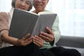 Happy smiling senior family couple in love reading book together, hugging embracing while spending free time at home on retirement Royalty Free Stock Photo