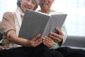 Happy smiling senior family couple in love reading book together, hugging embracing while spending free time at home on retirement Royalty Free Stock Photo