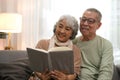 Happy smiling senior family couple in love reading book together, hugging embracing while spending free time at home on retirement Royalty Free Stock Photo