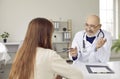 Happy, smiling senior male doctor giving a medical consultation to a young woman Royalty Free Stock Photo