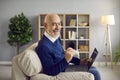 Happy, smiling senior man sitting on couch at home and using his laptop computer Royalty Free Stock Photo