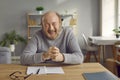 Happy smiling senior man sitting at table at home Royalty Free Stock Photo