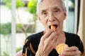 Happy smiling senior woman tasting mandarin deliciously,healthy asian old elderly opening her mouth to eat delicious organic Royalty Free Stock Photo