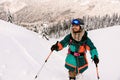 happy smiling skier in bright jacket is climbing the hill using skitour equipment.