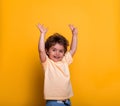 Happy smiling small child boy with hands up isolated on yellow background. Portrait of laughing little child Face of
