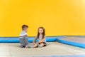 Happy smiling small kids sitting on indoor trampoline and playing in entertainment center Royalty Free Stock Photo