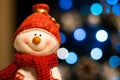 Happy smiling snowman wearing red scarf and hat with Christmas lights in the background Royalty Free Stock Photo