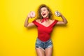 Happy smiling stylish woman with donutes on yellow background