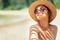 Happy smiling sun buthing woman in straw hat portrait. Palm tree shadows on the body. Health tanning concept