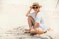 Happy smiling sunbathing woman in straw hat portrait. Palm tree shadows on the sand. Healthy tanning and vacation concept image