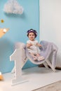 Happy smiling sweet baby girl sitting on armchair with shining light star, Birthday girl, One year old Royalty Free Stock Photo