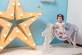 Happy smiling sweet baby girl sitting on armchair with shining light star, Birthday girl,  One year old Royalty Free Stock Photo