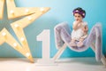 Happy smiling sweet baby girl sitting on armchair with shining light star, Birthday girl, One year old