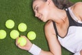 Happy Smiling Tanned Female Sportswoman Lying on Artificial Grass Surface Holding Tennis Ball