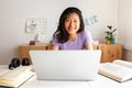 Happy, smiling teen asian female college student studying at home, doing homework using laptop looking at camera. Royalty Free Stock Photo