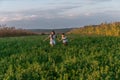 Happy smiling teen boy and girl in casual clothes holding hands together and running across the green field Royalty Free Stock Photo