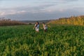 Happy smiling teen boy and girl in casual clothes holding hands together and running across the green field Royalty Free Stock Photo